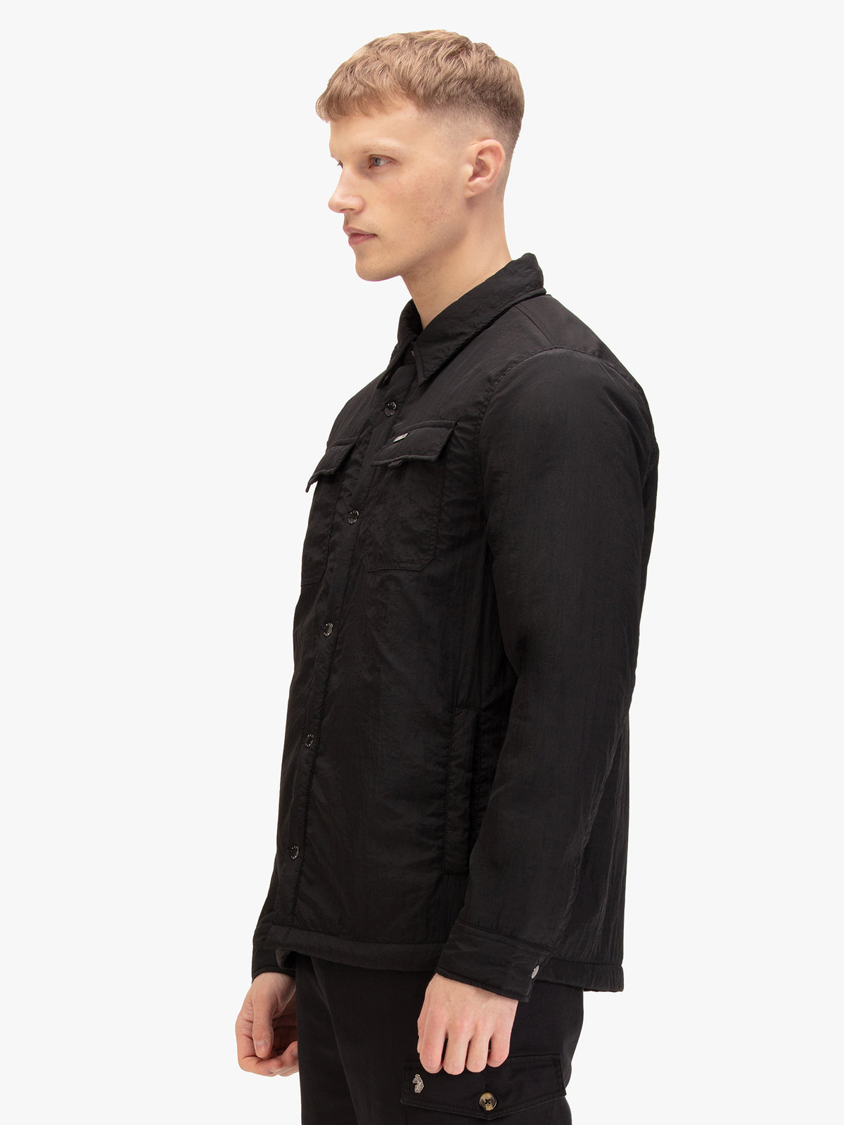 Men's black jacket with button-up front and front pocket, worn by a model, side view