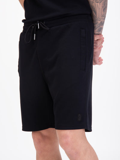 Men's black shorts with drawstring waistband, worn by a model, detail view