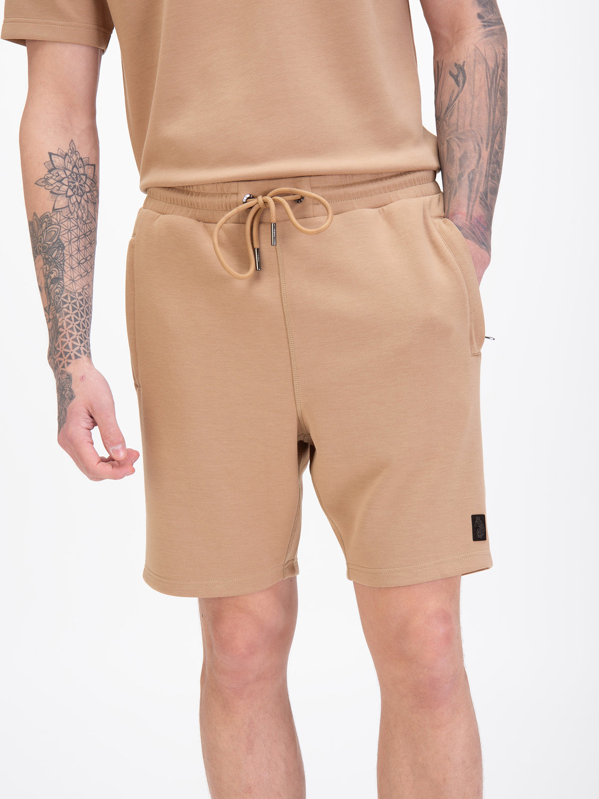 Men's beige shorts with drawstring waistband, worn by a model, detail view