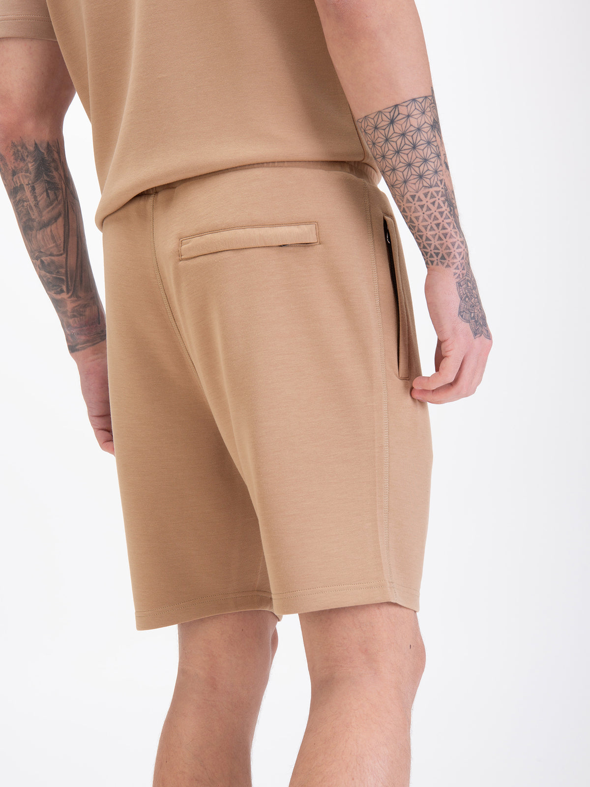 Men's beige shorts with drawstring waistband, worn by a model, detail view