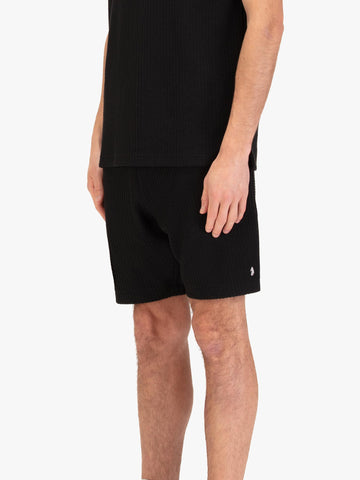 Men's black shorts with drawstring waistband, worn by a model, side view