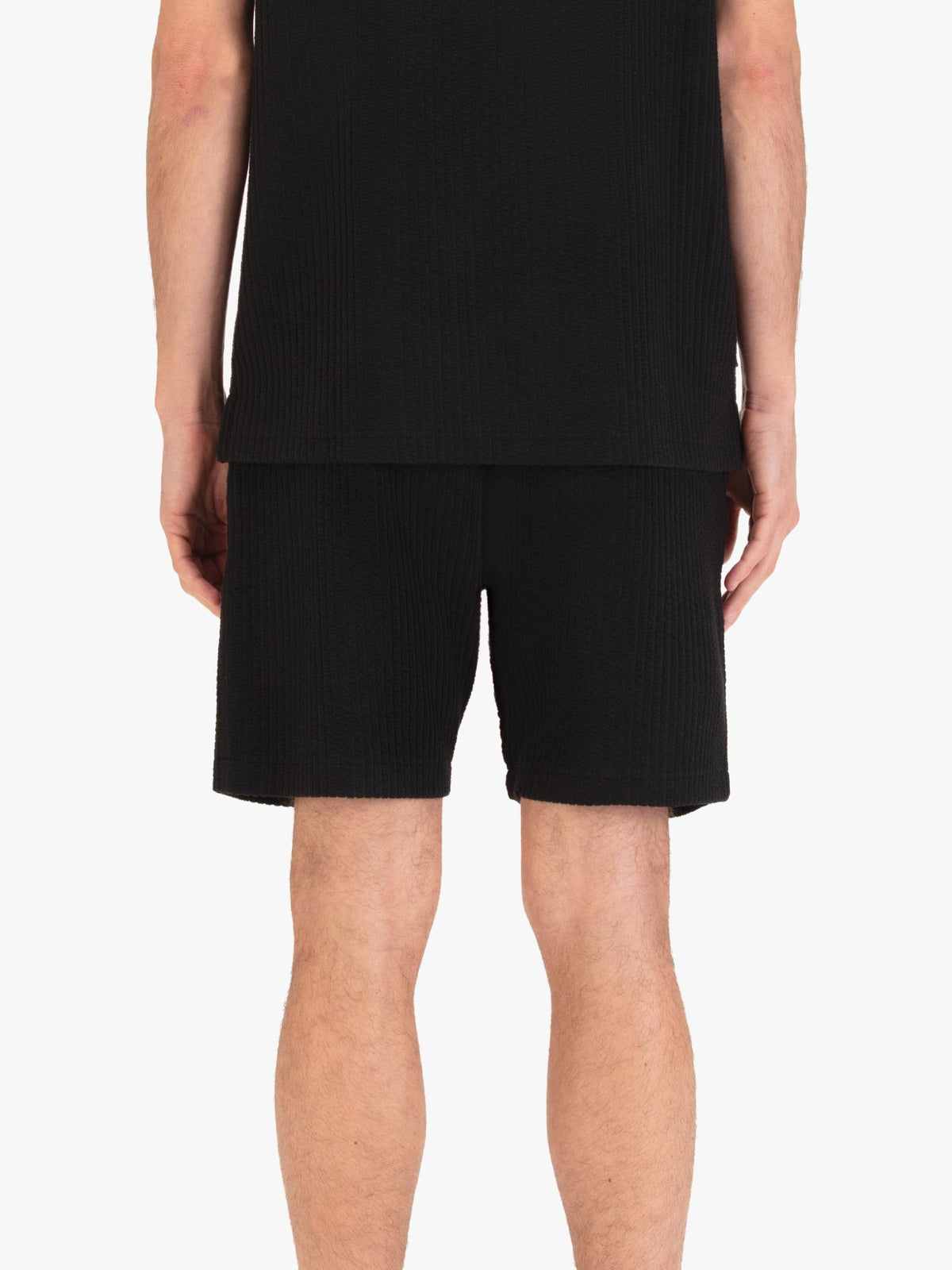 Men's black shorts with drawstring waistband, worn by a model, back view