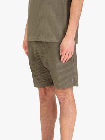 Men's green shorts with drawstring waistband, worn by a model, side view