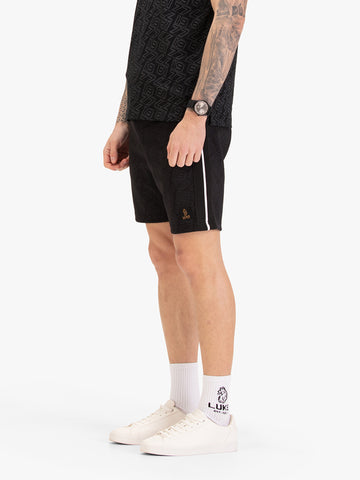 Men's black shorts with drawstring waistband, worn by a model, side view