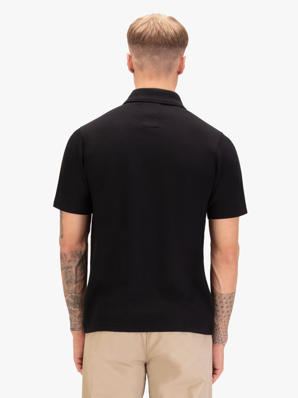 Men's black polo shirt with polo collar, worn by a model, back view