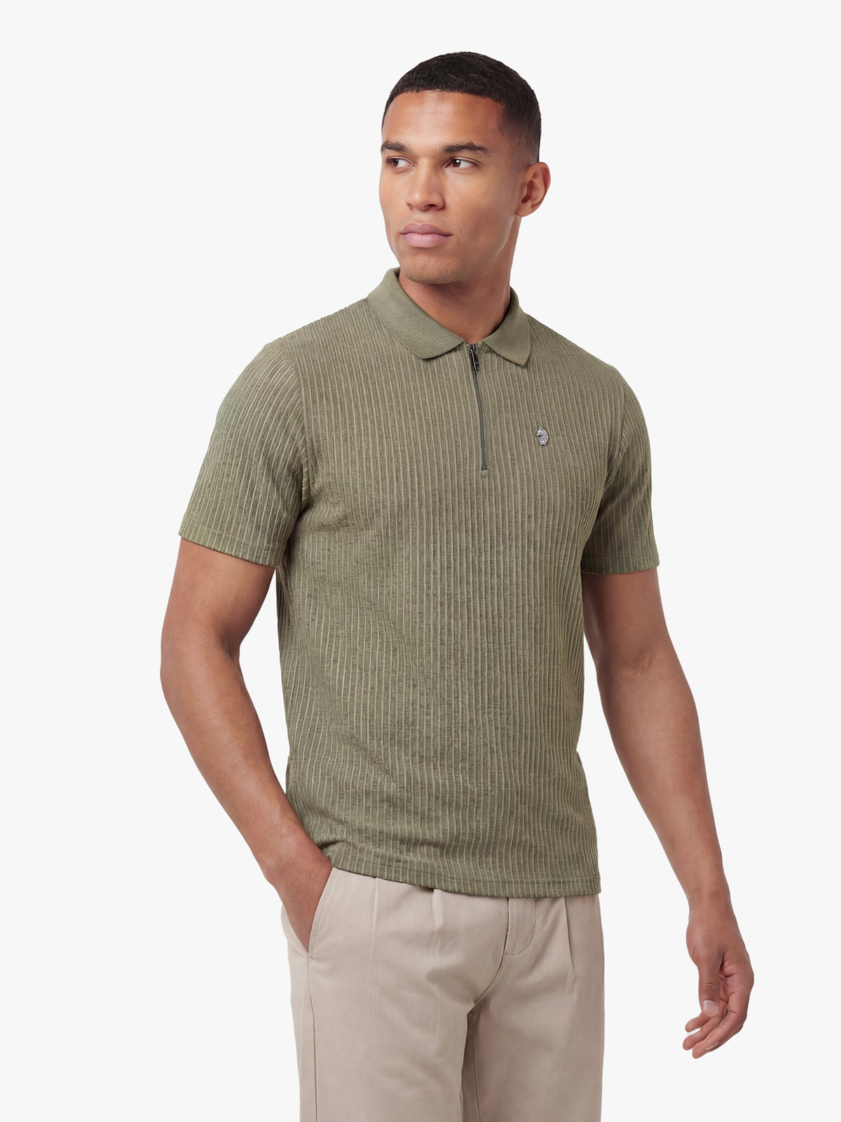 Man wearing clover green LUKE 1977 Waffle On 1000 jacquard zip neck polo with beige trousers, front view
