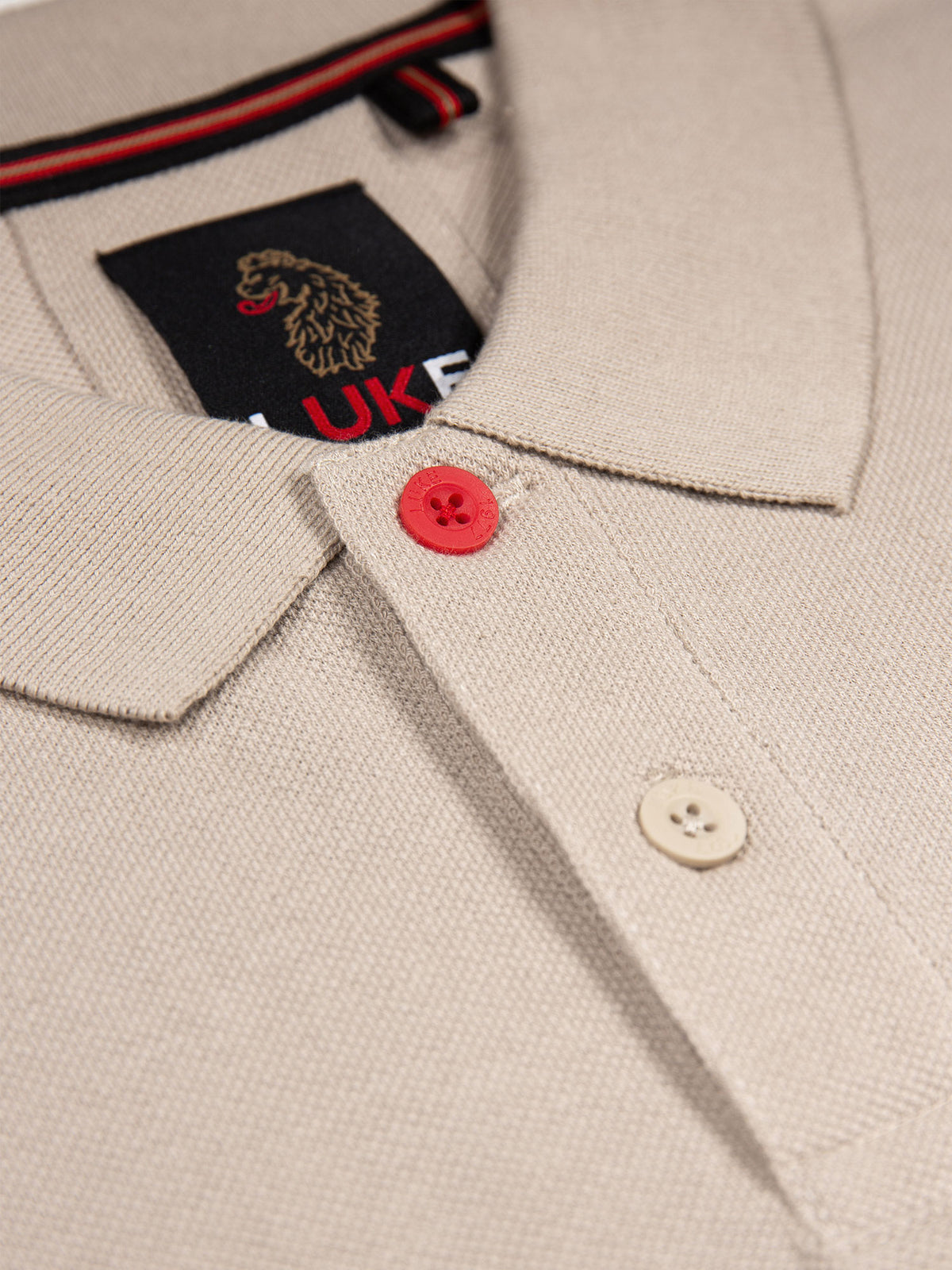 Close-up of marina red top button, smoke button and neck label on stone New Mead polo shirt