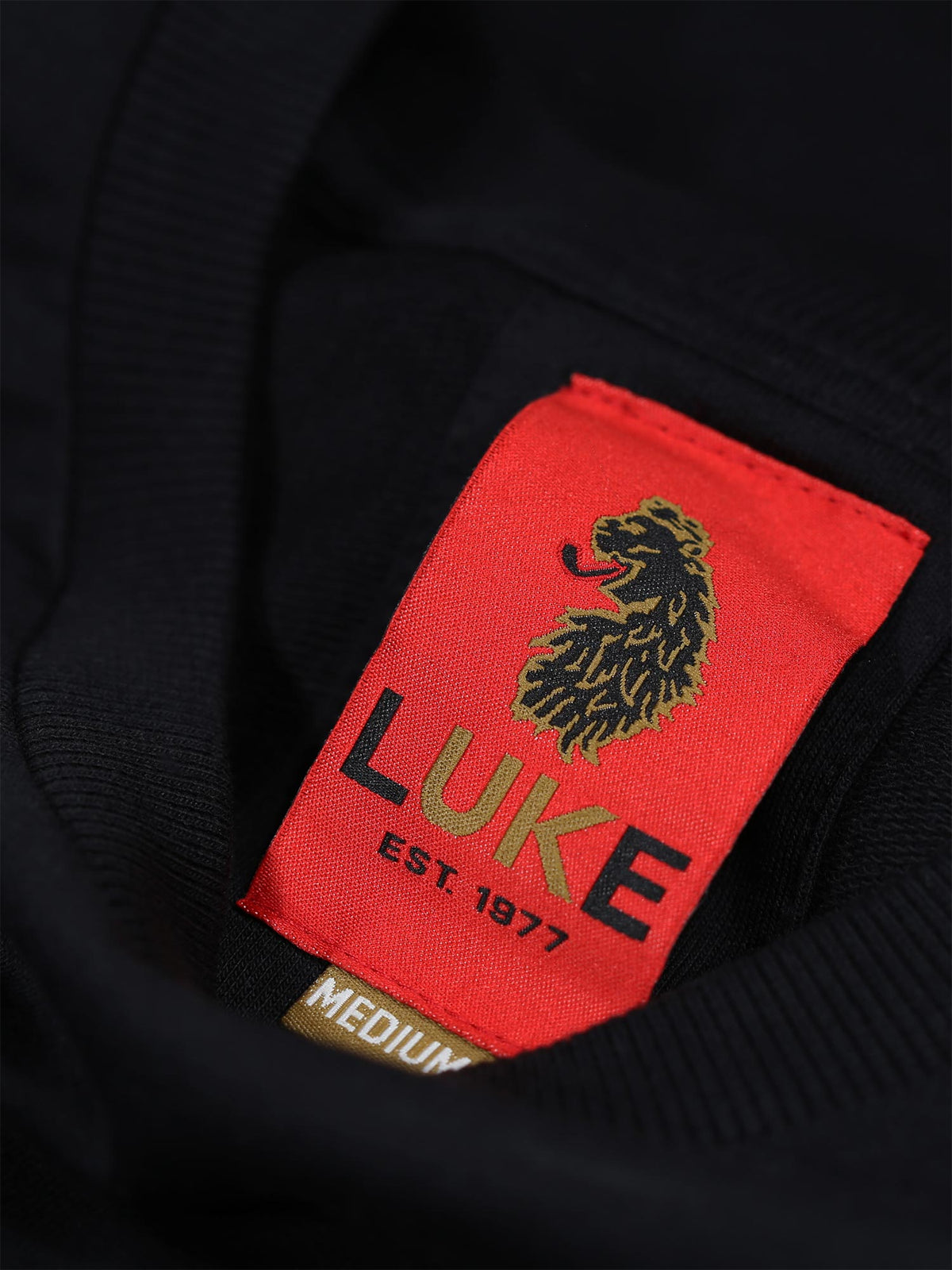 Close-up of red LUKE EST. 1977 neck label on black Dragger t-shirt